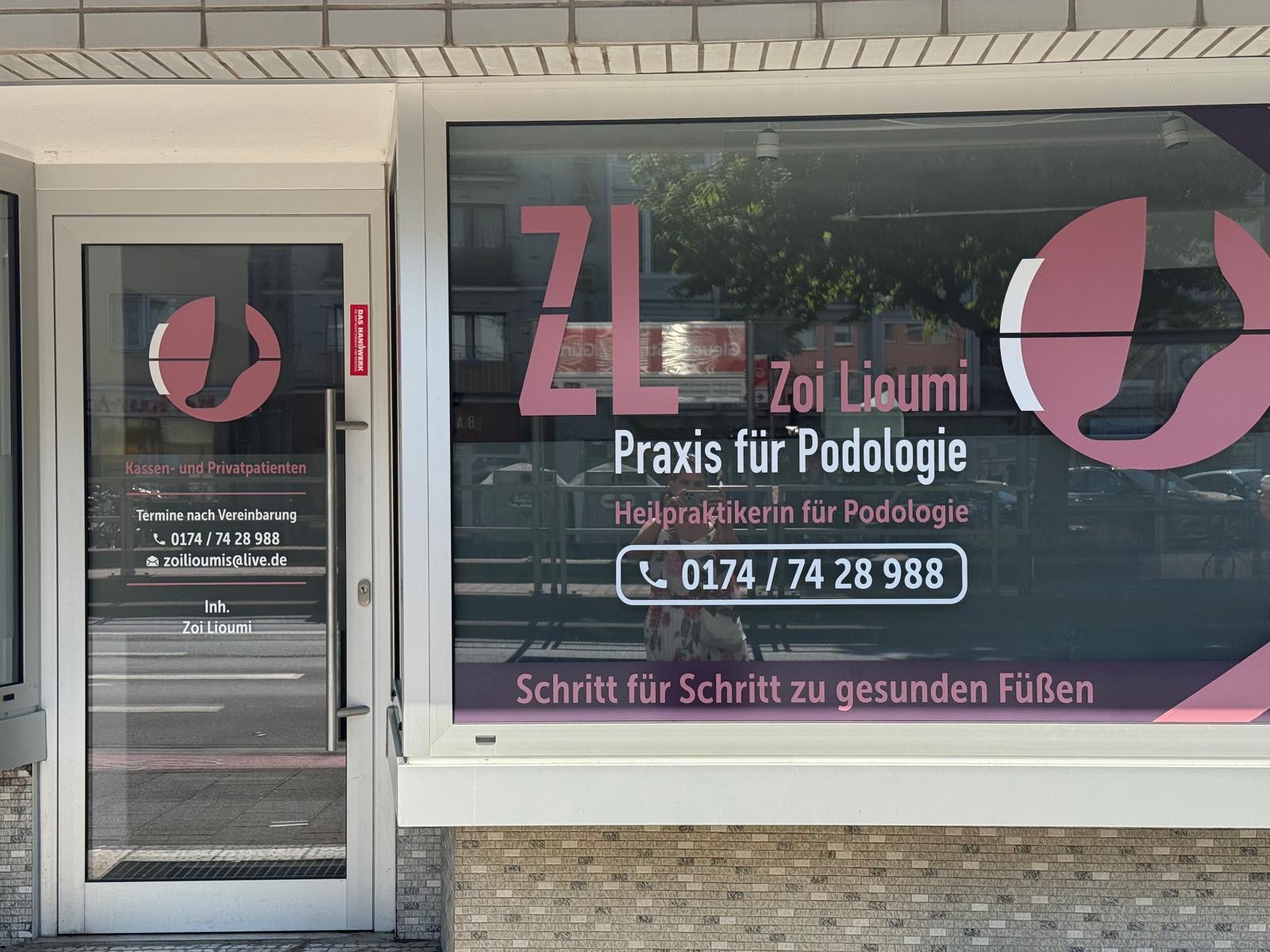 Schaufenster und Tür mit Zoi Liaoumi Logo in Rosa und Weiß auf Schwarz